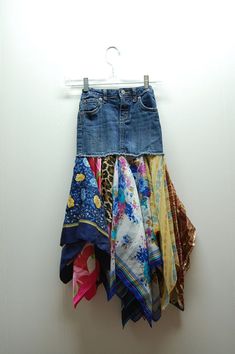 a pair of blue jean shorts hanging on a white wall next to other clothing items