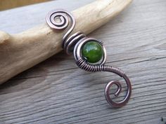 a piece of jewelry sitting on top of a wooden table next to a tree branch