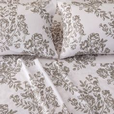 the bed is made with white and brown flowers on it's comforter cover