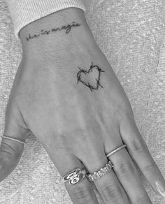 a woman's hand with a heart tattoo on it