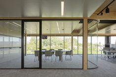 an office building with glass walls and tables in the foreground, surrounded by chairs