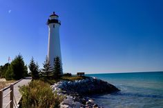 a light house sitting on top of a rocky shore next to the ocean and trees