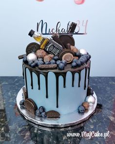 a blue and white cake with chocolate drips on it's top, topped with cookies