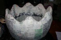 a large white vase sitting on top of a table next to a pile of papers