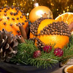 an arrangement of oranges, pine cones and other holiday decorations on a wooden table