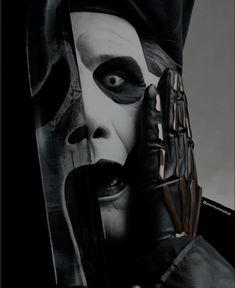 a close up of a person wearing a mask and holding their hands to his face