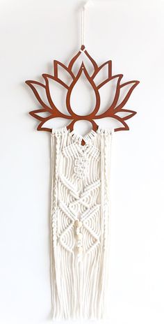 a white wall hanging with a wooden lotus decoration on it's side and a string attached to the back