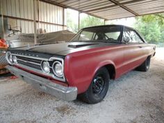 an old red and black car parked in a garage