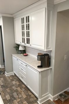 a kitchen with white cabinets and marble counter tops