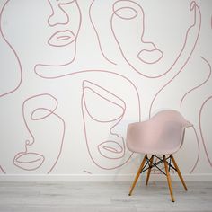 a pink chair sitting in front of a wall with lines on it and faces painted on the wall