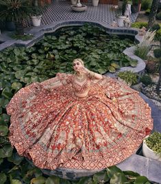 a woman sitting on top of a lush green field next to water lilies and lily pads