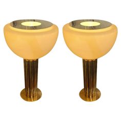 a pair of yellow glass and brass pedestals with lights on each side, set against a white background