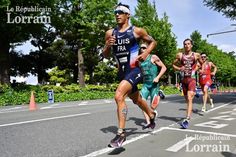 a group of men running down a street next to trees