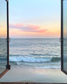 an open window looking out onto the ocean at sunset with waves coming in from the beach