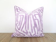 a purple and white pillow sitting on top of a wooden floor