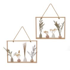 two wooden hanging frames with dried flowers and plants in vases on the sides, one holding a string