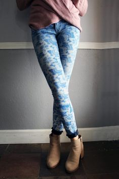 a woman is leaning against a wall with her hands on her hips and wearing blue patterned leggings