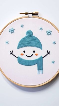 a cross stitch snowman with a blue hat and scarf