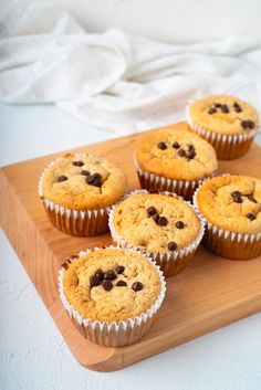 six muffins on a wooden tray with white cloth