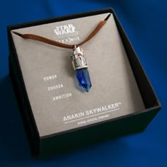 a necklace in a box with a star wars pendant on it's cord that is attached