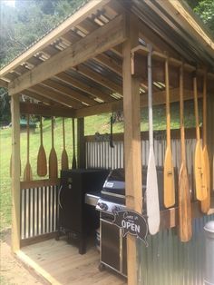 an outdoor bbq with paddles hanging from it's roof and grilling area