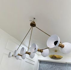 a chandelier hanging from the ceiling in a room with white walls and gold fixtures