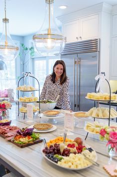 a woman standing in front of a table filled with plates and trays of food