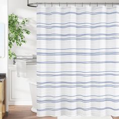 a white shower curtain with blue lines on it in a bathroom next to a toilet