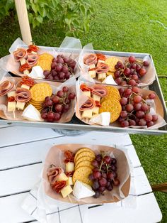 grapes, crackers and cheese are arranged on trays