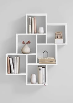 a white shelf with books and vases on it