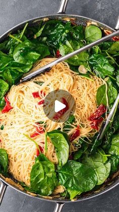 a pan filled with pasta and spinach on top of a table next to utensils