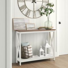 a clock on the wall next to a shelf with pictures and plants in front of it