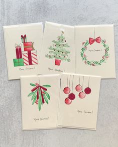 four christmas cards with watercolor designs on them, each featuring a tree and presents