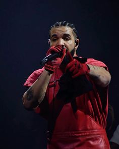 a man in a red shirt and black gloves holding a microphone up to his mouth