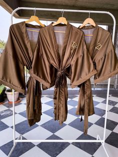 three brown robes are hanging on a rack