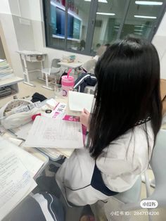 a woman sitting at a desk with papers in front of her and writing on a piece of paper