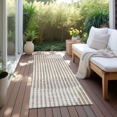 a white couch sitting on top of a wooden floor next to a lush green forest