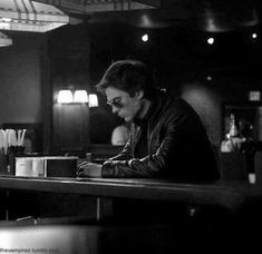 a man sitting at a bar writing on a piece of paper