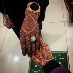 a close up of a person's hand with henna tattoos on it and a watch