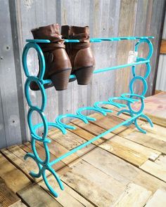 a pair of brown boots are hanging on a blue metal shoe rack that is made out of wood planks