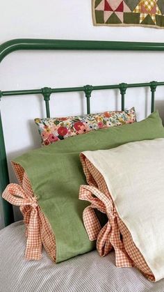 a green headboard with two pillows on top of it and a quilt hanging above the bed