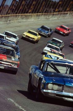 a group of cars driving around a track in a race, with one car turning the corner