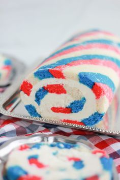 red, white and blue cake roll on a silver platter with spoons next to it