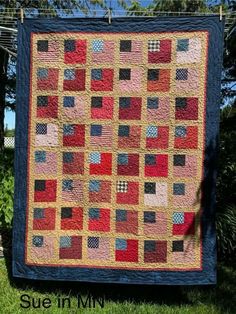 a quilt hanging on a clothes line in the grass