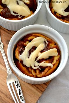 two white bowls filled with cinnamon buns covered in icing next to a fork