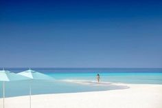 a person standing on the beach with an umbrella