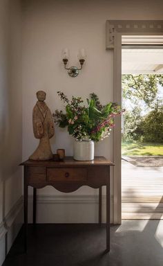 a wooden table topped with a potted plant next to a statue on top of it