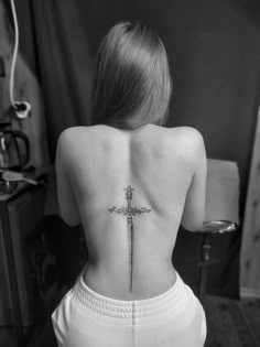 a woman's back with a cross tattoo on her lower back and the upper part of her body