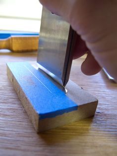 a person using a knife to cut something on a piece of wood with a sharpener