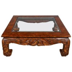 a wooden coffee table with glass top and carvings on the bottom, sitting against a white background